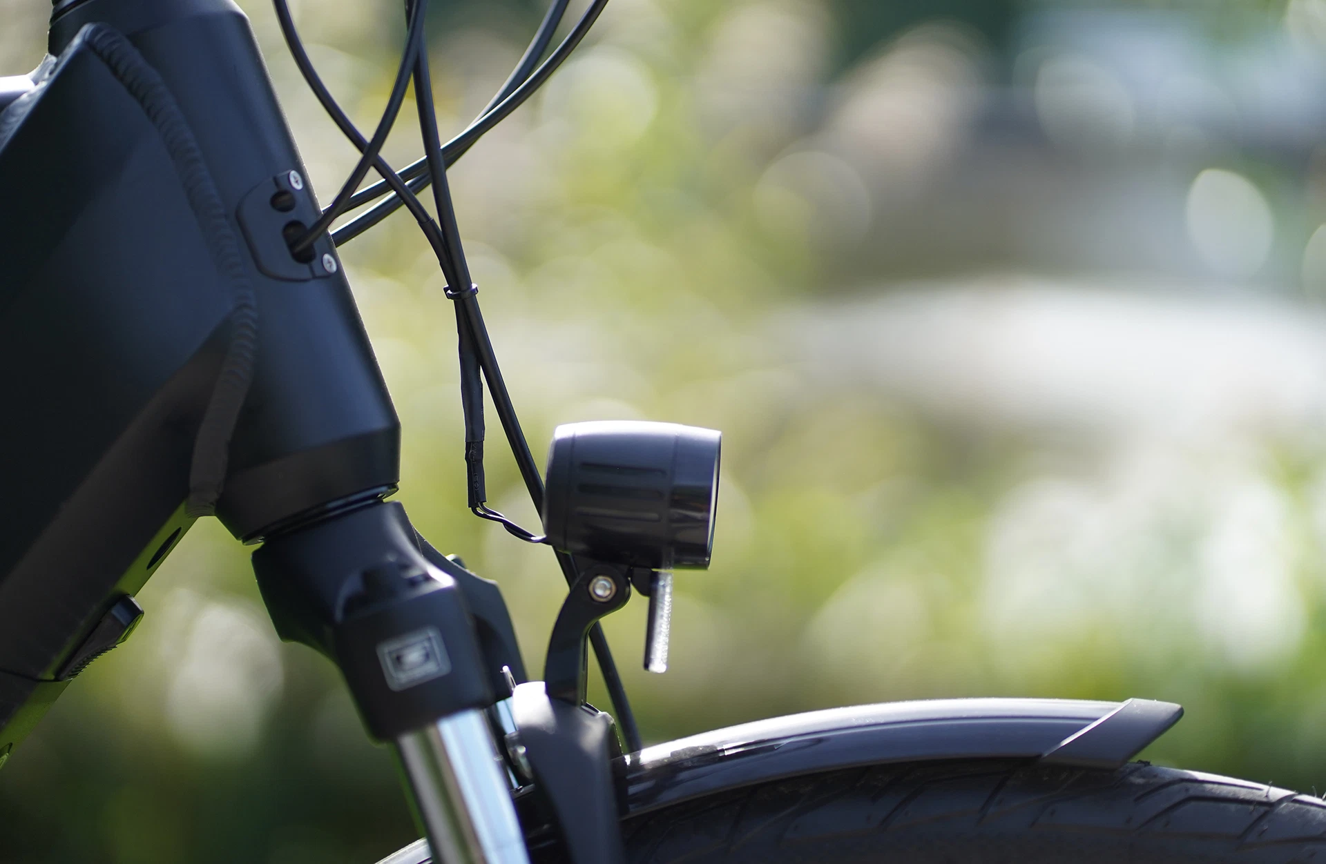 Bildausschnitt Detailansicht Scheinwerfer mit Reflektor, Steuerrohr und Federgabel im Anschnitt vor unscharfem Naturhintergrund