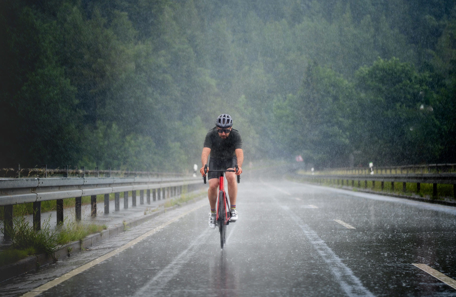 Rennradfahrer bei Regen auf Landstraße