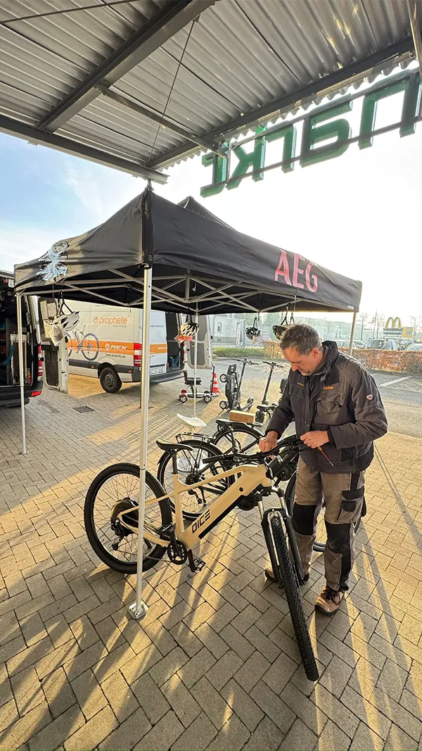 Prophete Wintercheck-Service unter schwarzem AEG-Pavillon, Mitarbeiter prüft ein DICE-MTB vor einem Prophete-Servicefahrzeug.