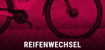 Nahaufnahme eines platten Fahrradreifens auf Kopfsteinpflaster, roter Hintergrund, Text Reifenwechsel