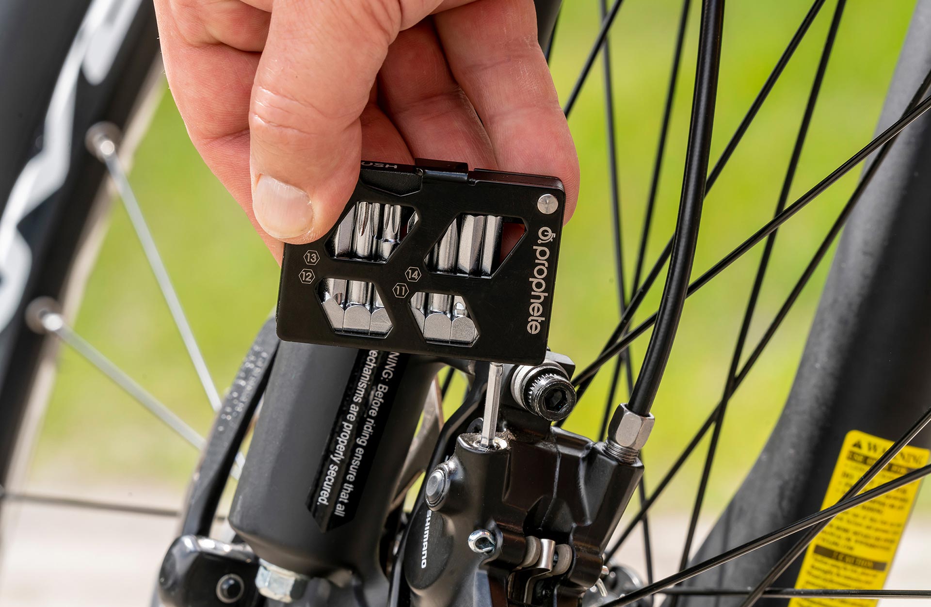 Multitool schwarz wird verwendet um eine Schraube an der Bremsanlage anzuziehen - seitliche Detailansicht
