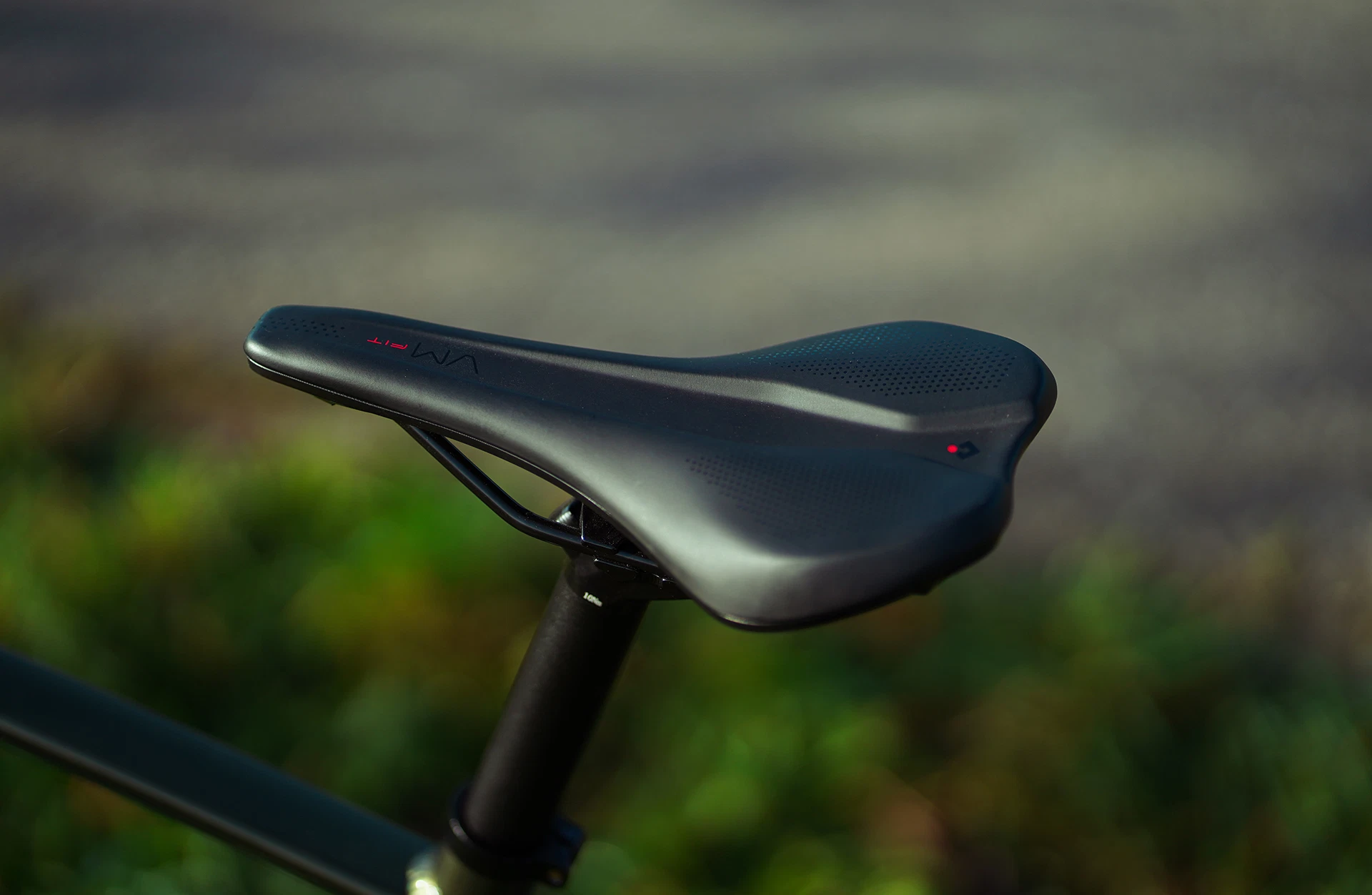 Bildausschnitt Sattel auf Sattelstütze mit Rasen und grauem Boden im Hintergrund (unscharf)