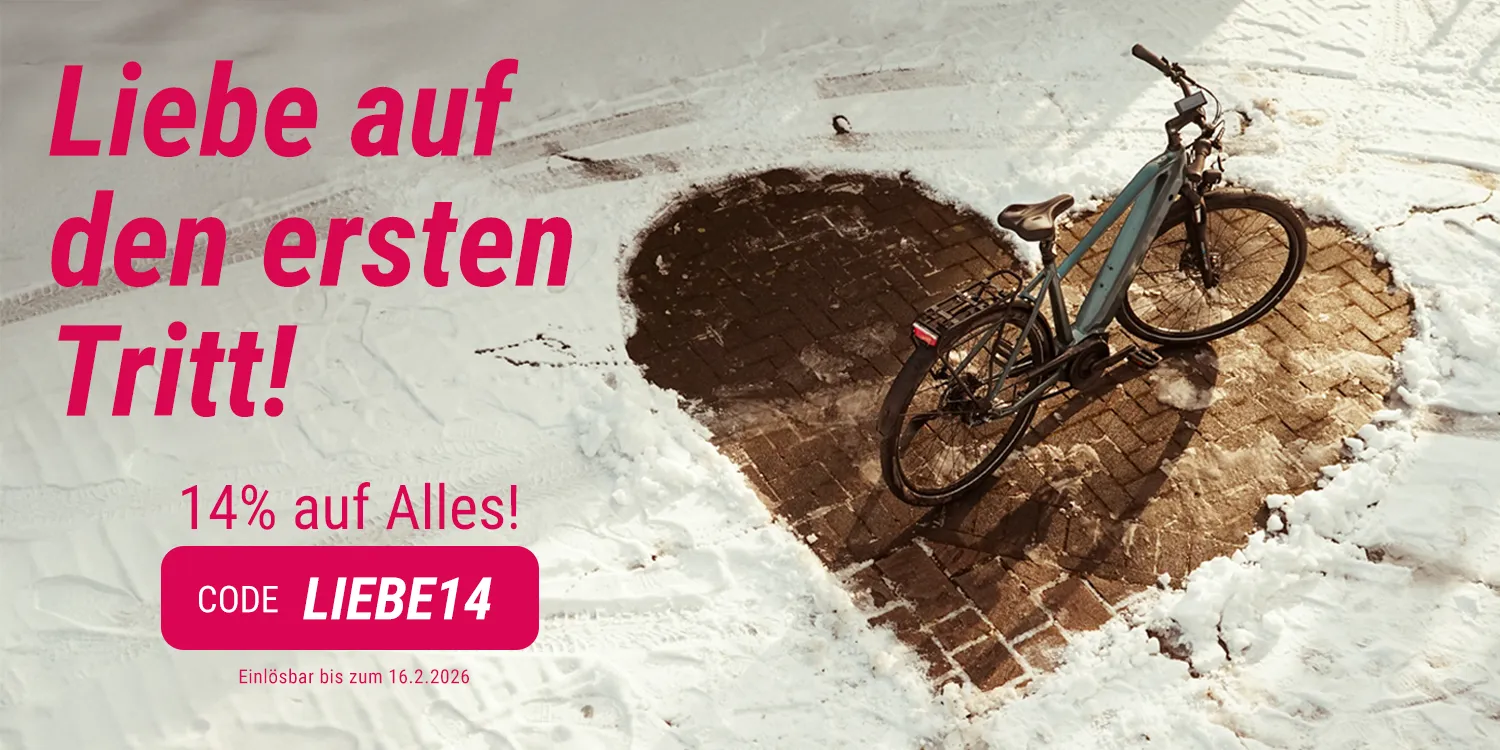 E-Bike steht auf herzförmig freigeschaufelter Fläche im Schnee neben Valentinstags-Rabattaktion