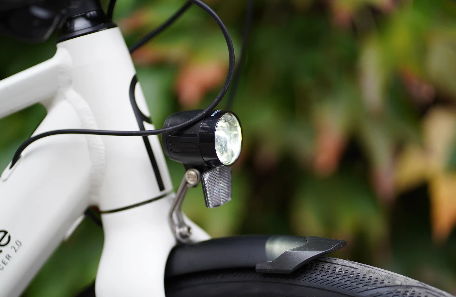 Bildausschnitt Frontscheinwerfer, an der Gabel mit integriertem Schutzblech vor natürlichem Hintergrund mit Blättern