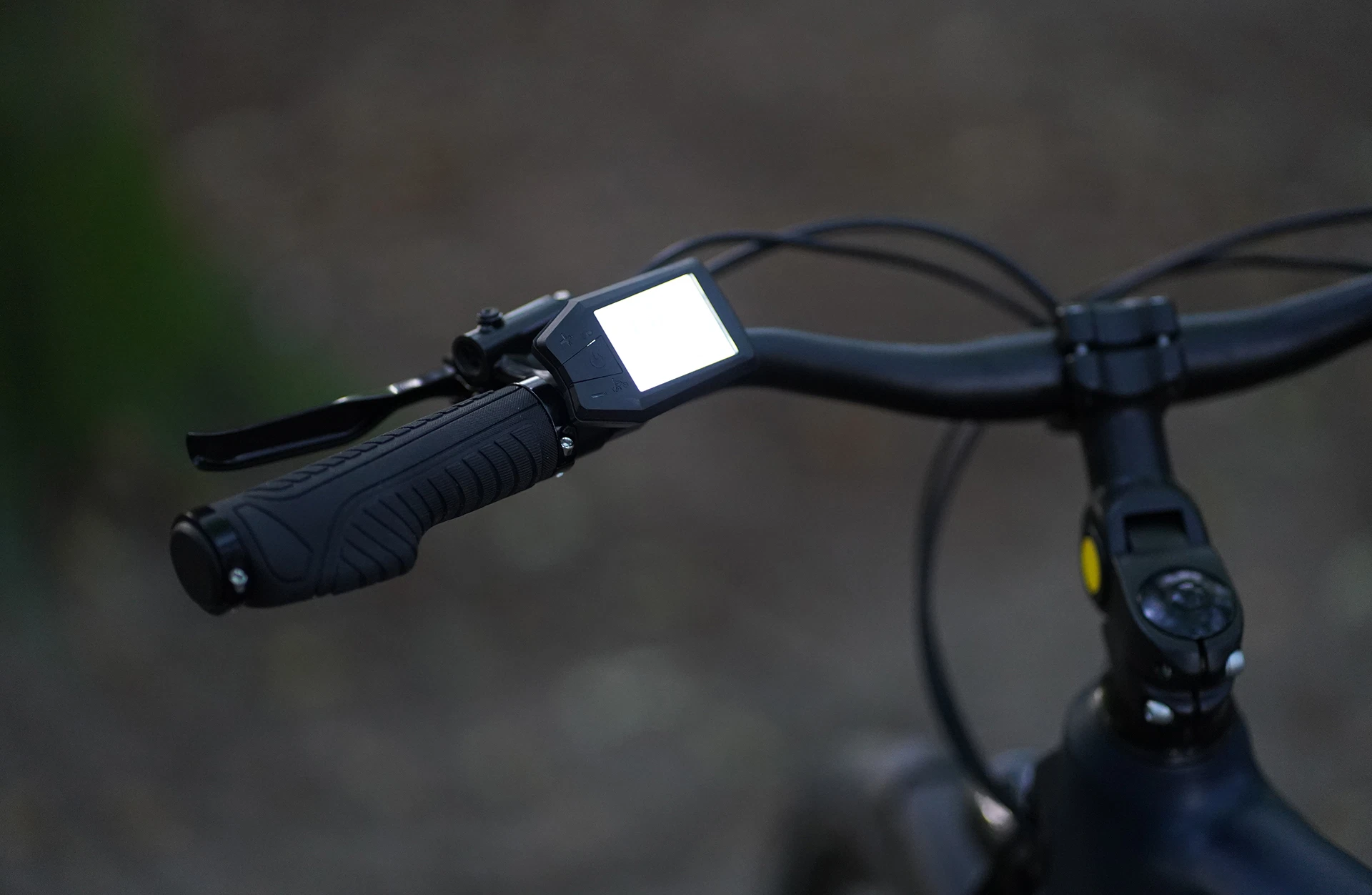 Bildausschnitt Detailansicht Lenker im Anschnitt mit Bremshebel, geschraubtem Ergogriff und LCD Display mit Bedieneinheit an winkelverstellbarem Vorbau vor unscharfem Hintergrund