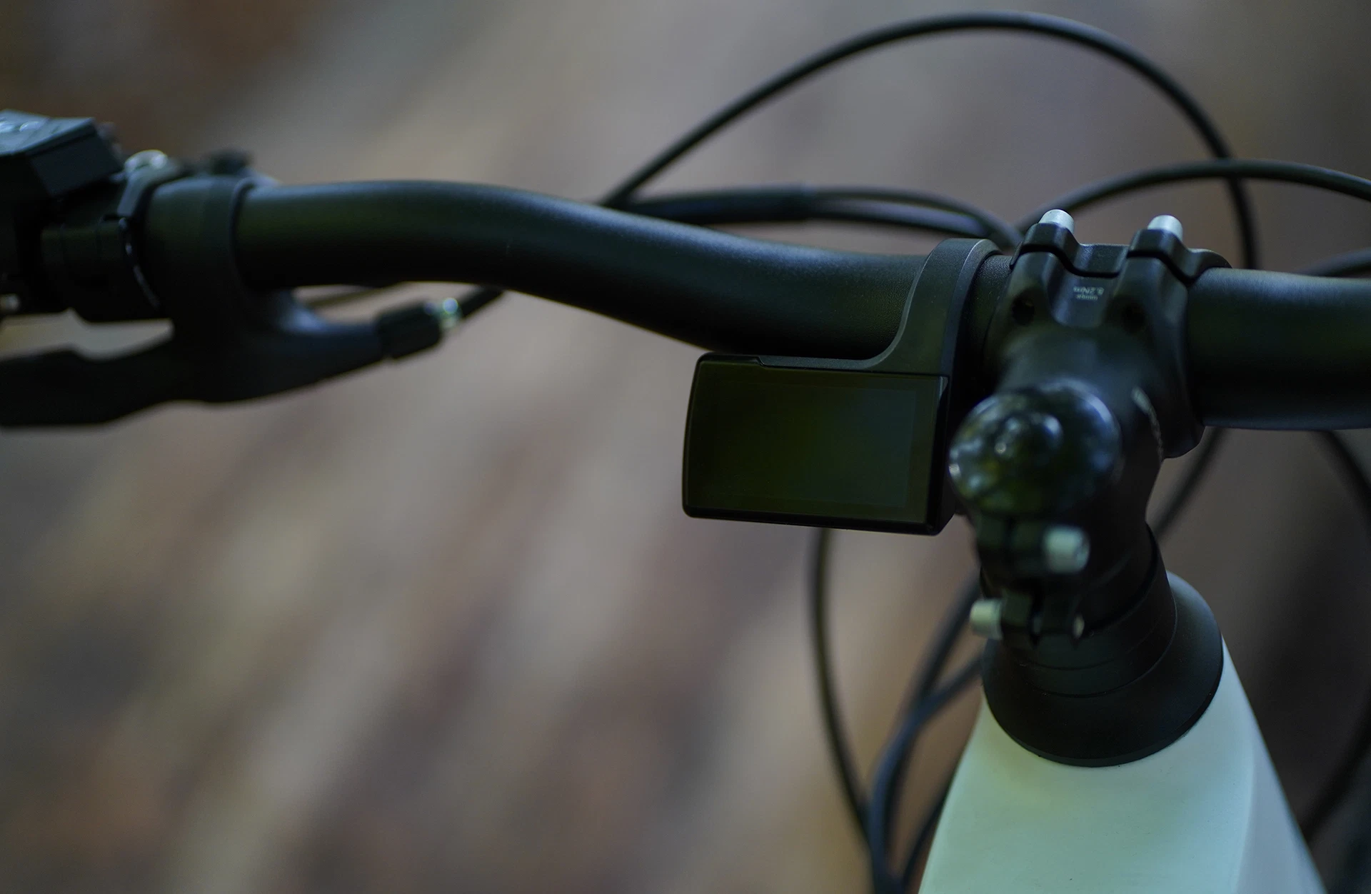 Bildausschnitt TFT-Display ausgeschaltet neben A-Head Vorbau am Lenker vor unscharfem Untergrund