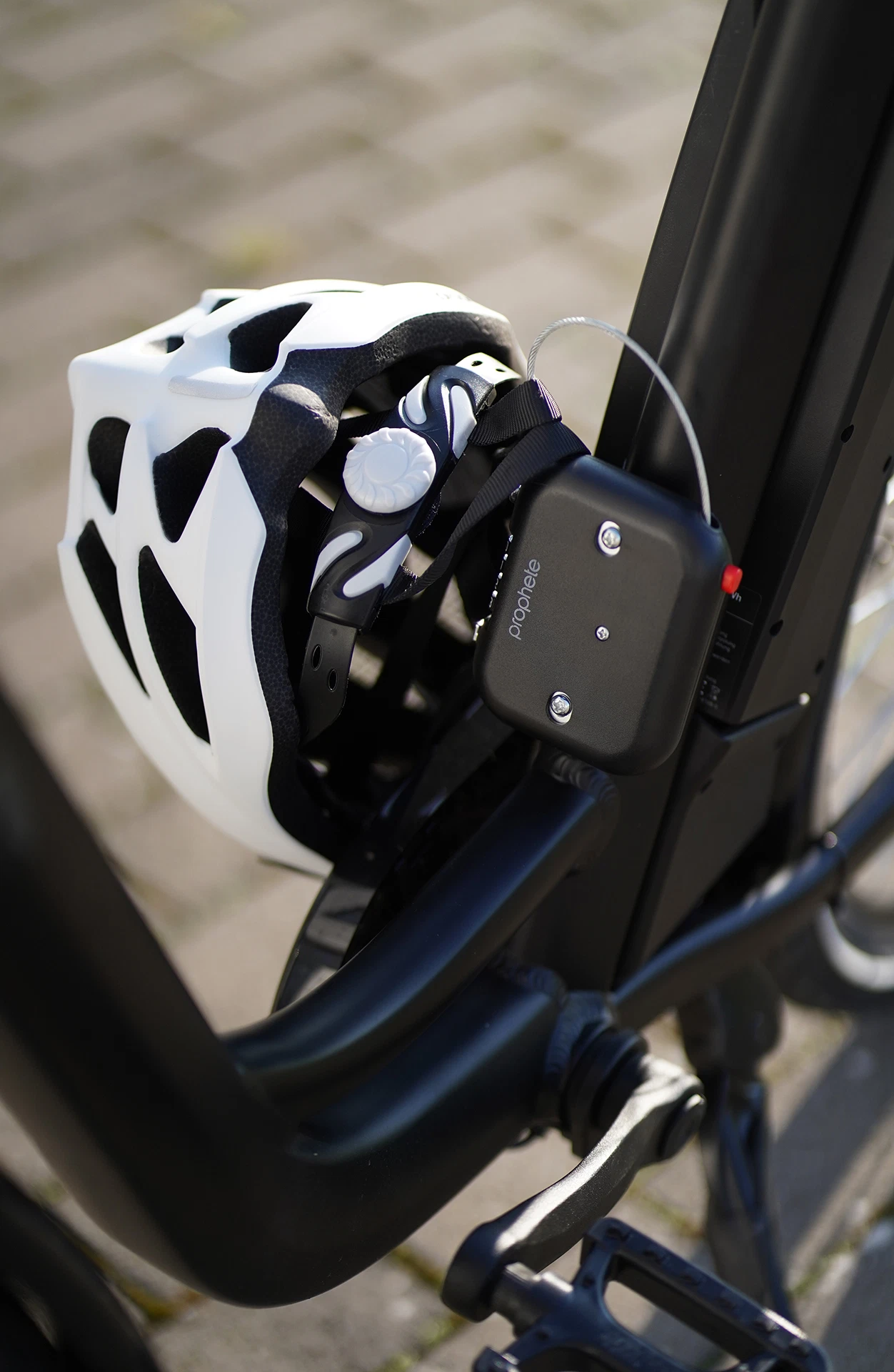 Helmschloss schließt weißem Fahrradhelm an Rad ab - seitliche Ansicht