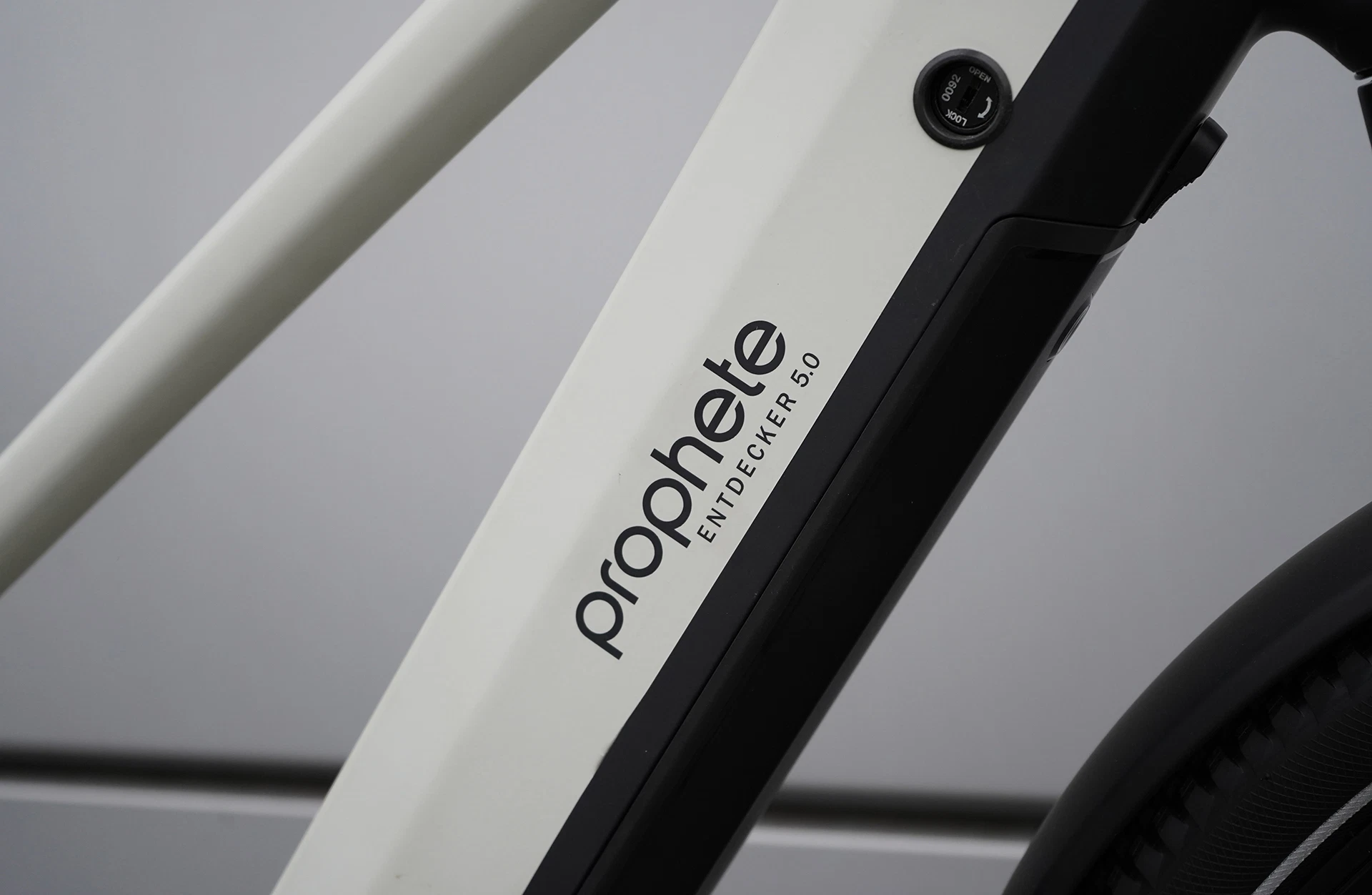Bildausschnitt Seitliche Nahaufnahme des Unterrohrs mit Prophete-Logo und Modellschriftzug Entdecker 5.0 am weißen Rahmen vor Metallwand