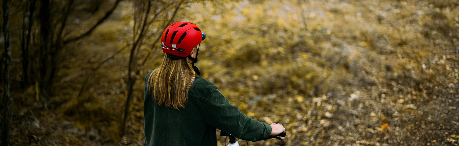 Fahrradfahrer mit rotem Helm im herbstlichen Wald – Helm richtig tragen für mehr Sicherheit beim Radfahren