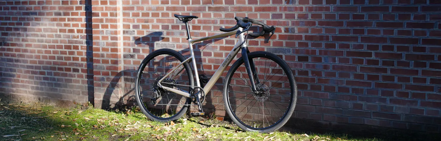 Gravelbike im Sonnenlicht vor einer Backsteinwand abgestellt