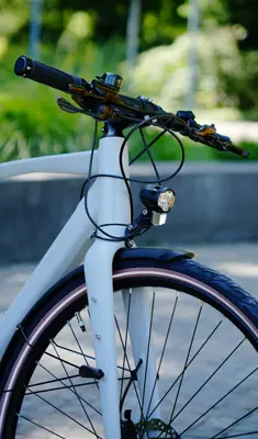 Lenker und Vorderpartie eines weißen Urbanicer E-Bike mit Vorderlicht und Schutzblech im Außenbereich