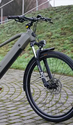 E‑Bike Vorderansicht mit Federgabel, Scheibenbremse und Vorderrad auf Kopfsteinpflaster