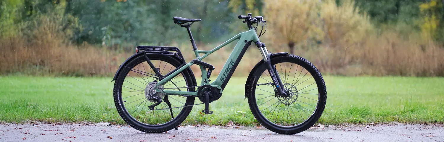Grünes SUV-E-Bike mit robusten Reifen, seitlich auf einem Weg in natürlicher Umgebung