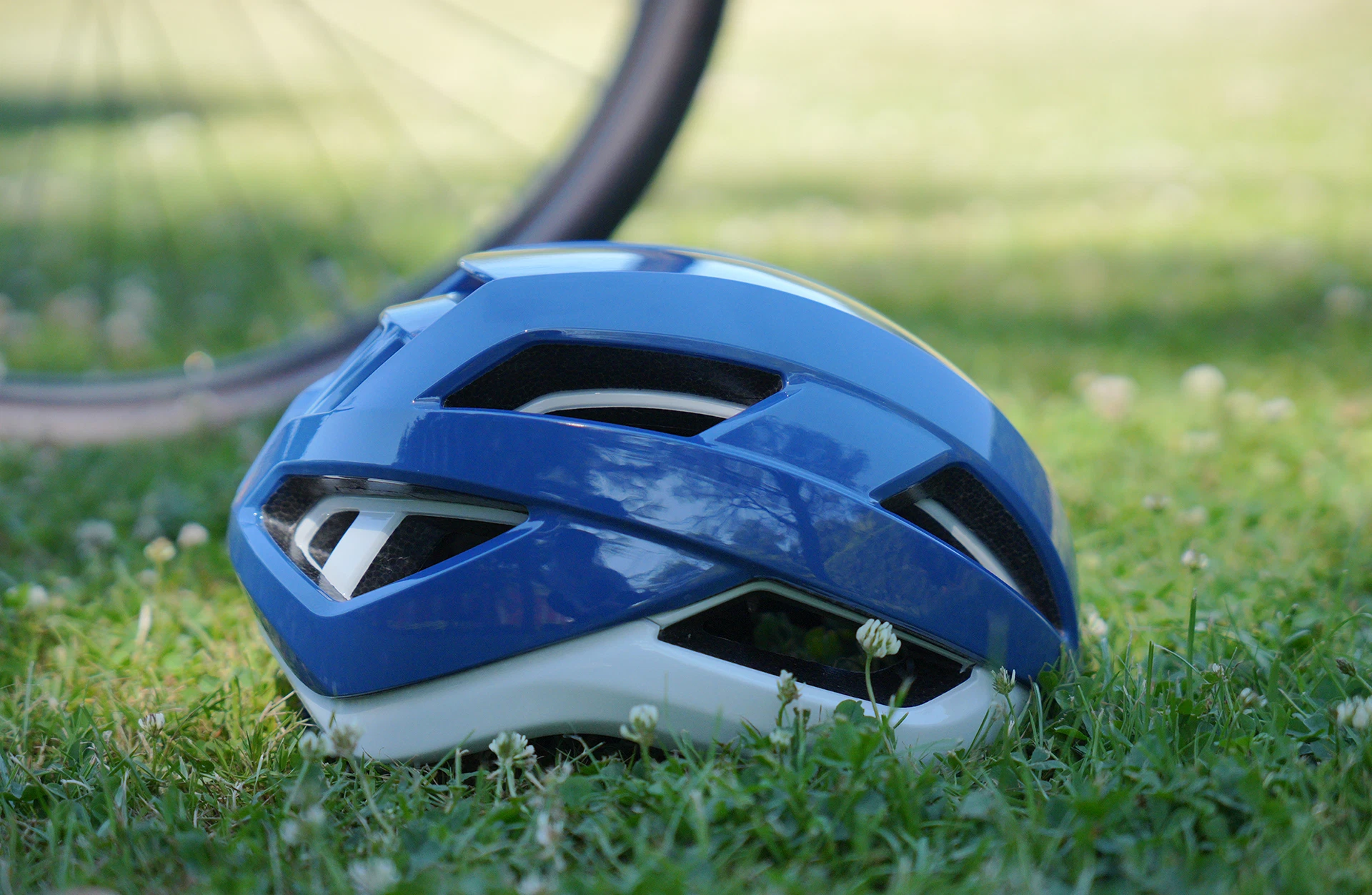 Seitliche Ansicht ProShield Helm für Fahrrad und E-Bike auf Rasenfläche mit Fahrradreifen im Hintergrund