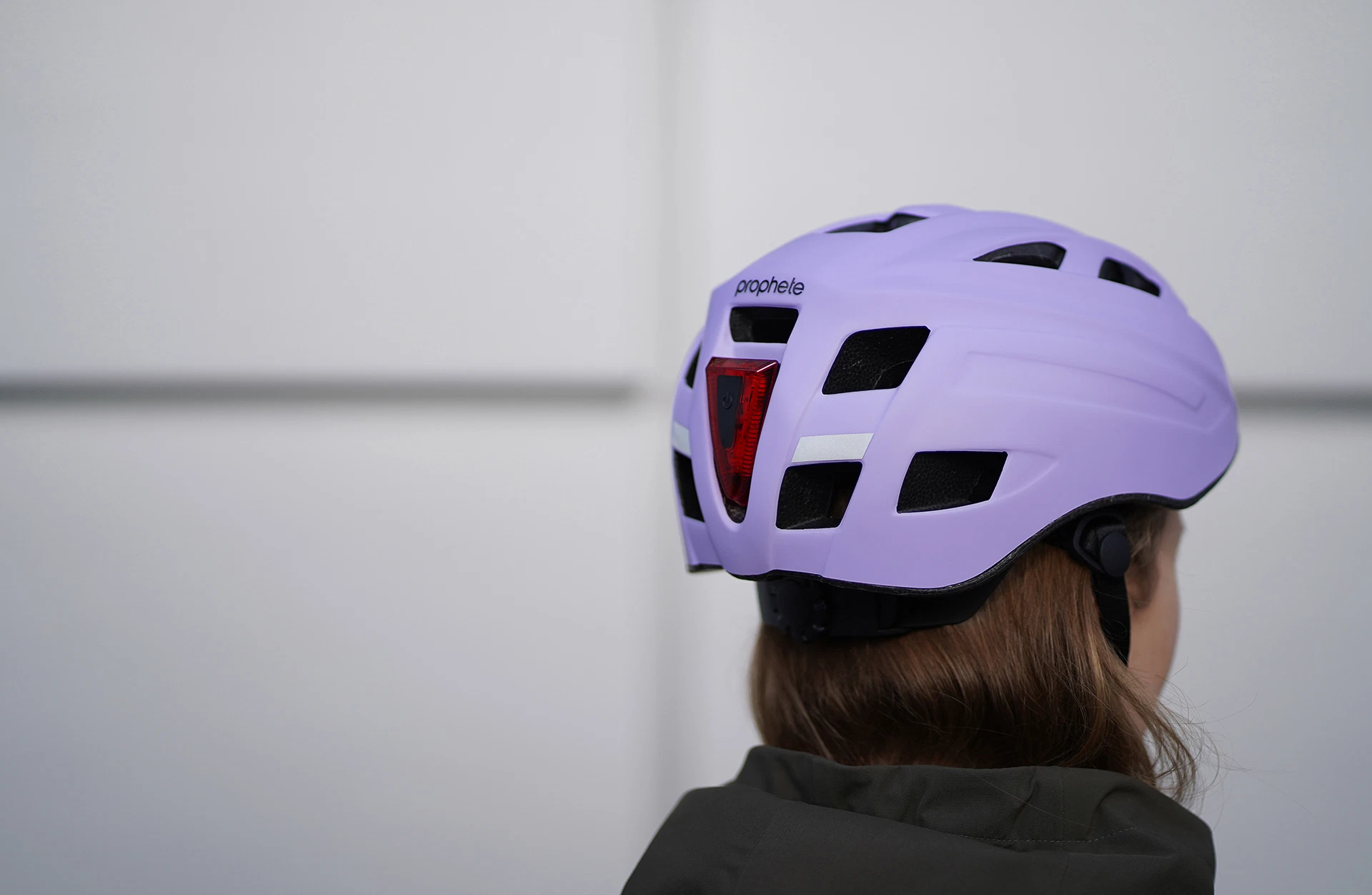 Fahrradhelm lila getragen von Model vor grauem Hintergrund - seitliche Ansicht