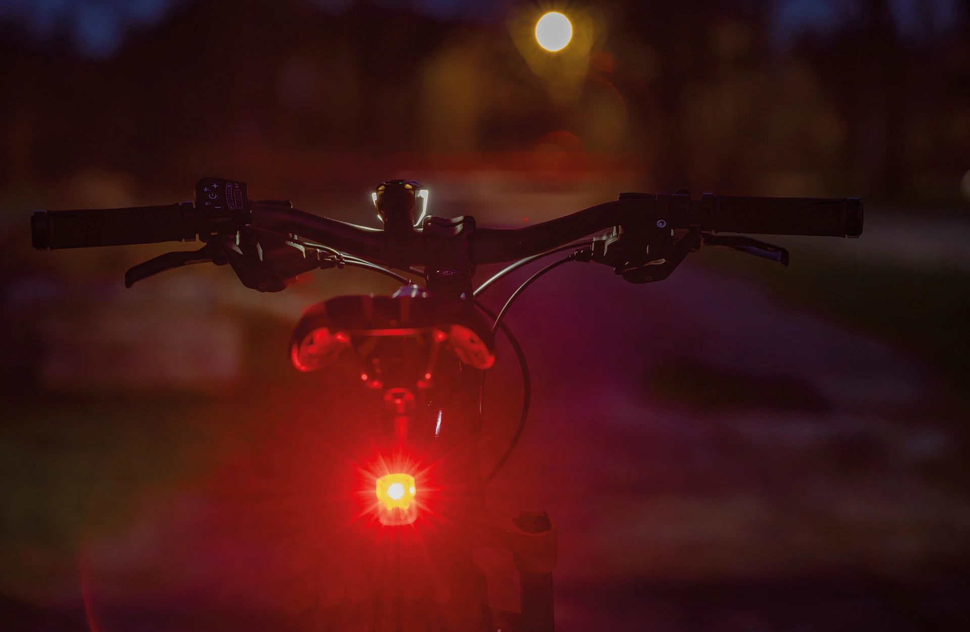 Rücklicht rot an Fahrrad montiert leuchtet im dunkeln - Ansicht von hinten im Freien