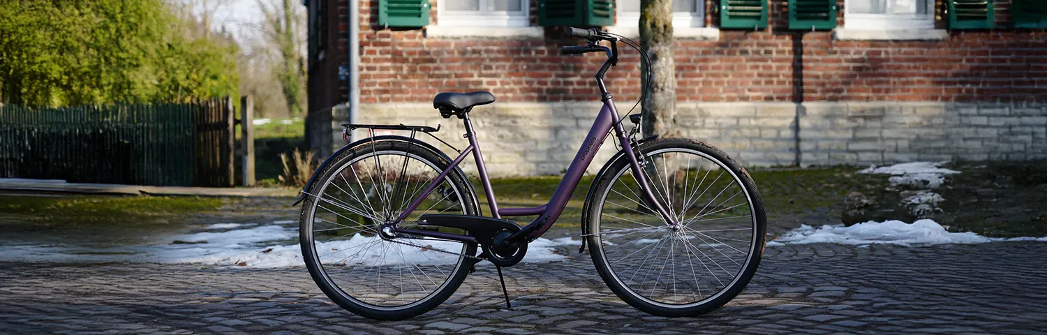 City Bike auf gepflastertem Hof vor Backsteinwand mit grünen Fensterläden