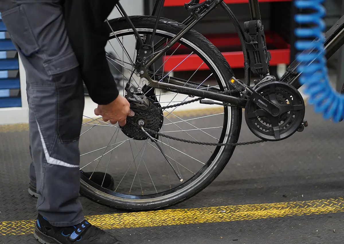 Hinterrad wird angebracht am Heck des E-Bikes mit Werkstattboden im Hintergrund