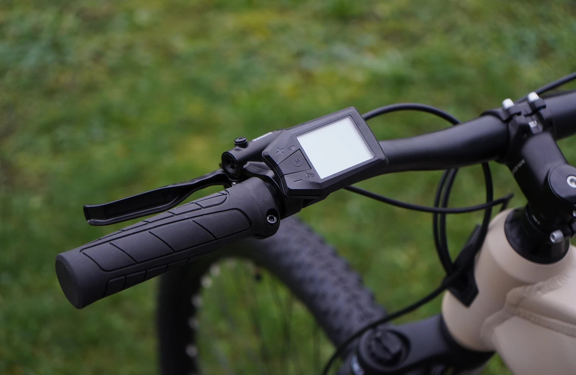 Linker Fahrradlenker mit Display und Bedieneinheit, schwarzer Griff mit Rillen, Bremshebel, Teil vom Rahmen sichtbar