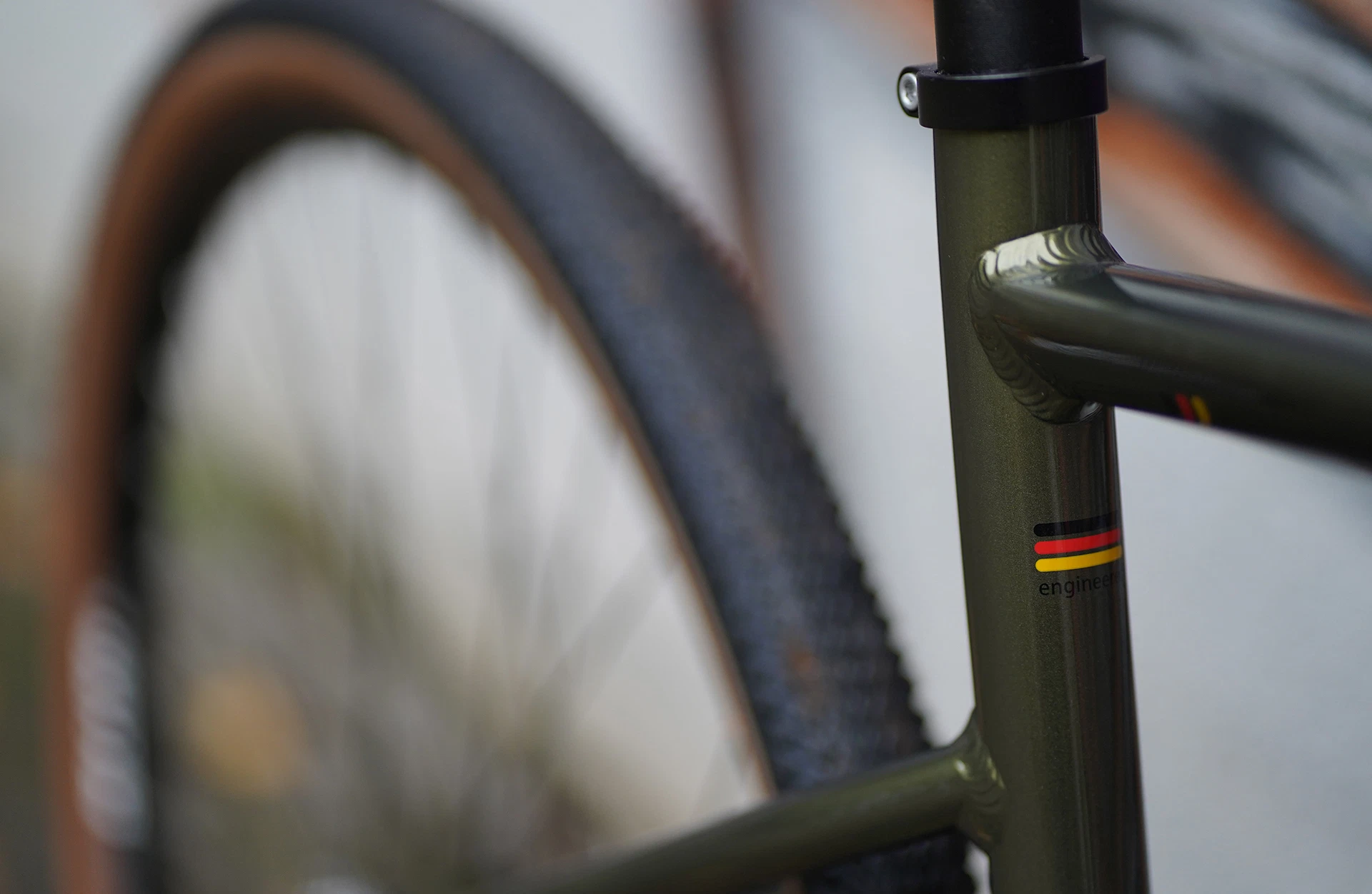 Bildausschnitt Hinterbau in Nahaufnahme mit unscharfem Hinterrad im Hintergrund und Deutschlandfahne und Engineering Icon auf Sitzrohr