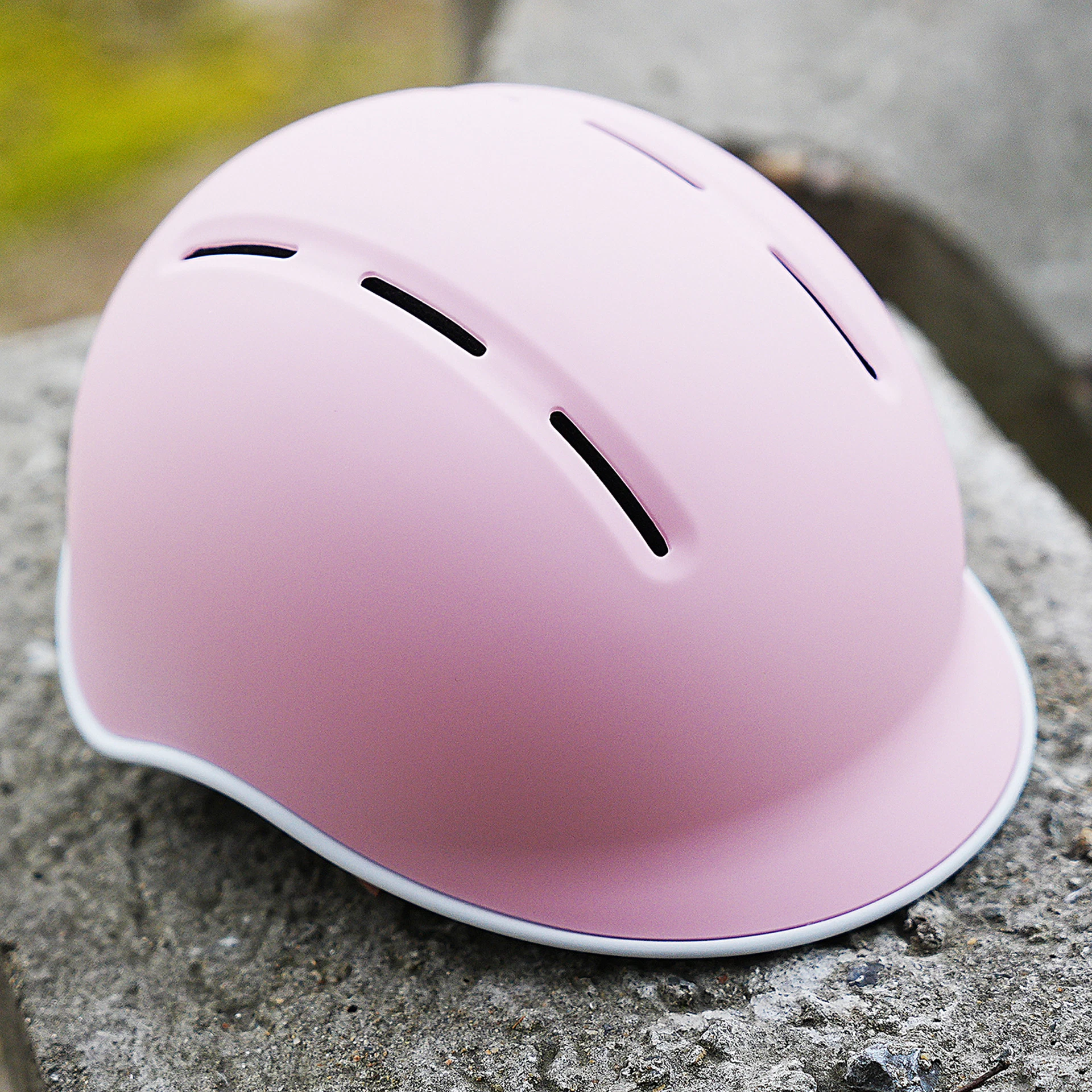 Fahrradhelm rosa auf Stein liegend im Freien