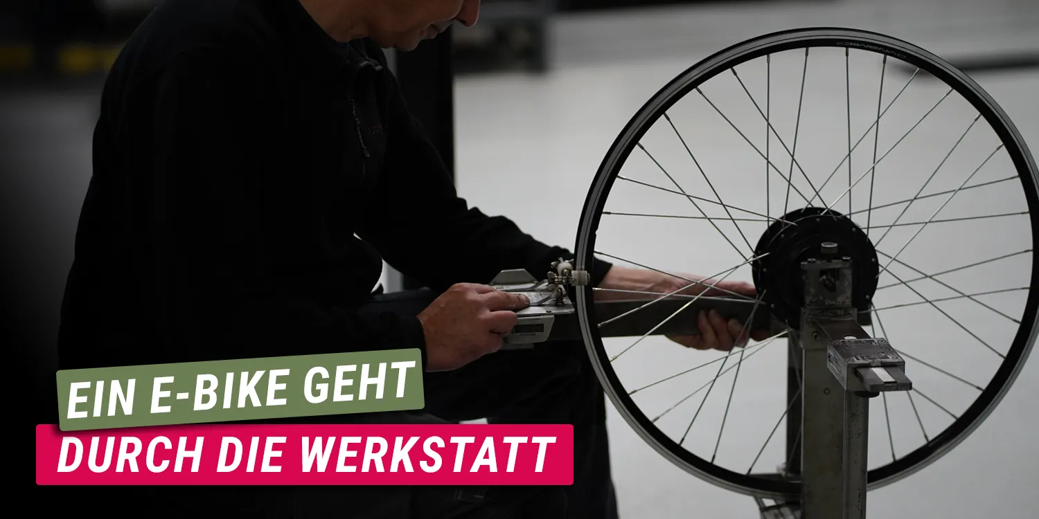 Person prüft ein ausgebautes E‑Bike‑Rad in einer Werkstatt, Text Ein E‑Bike geht durch die Werkstatt