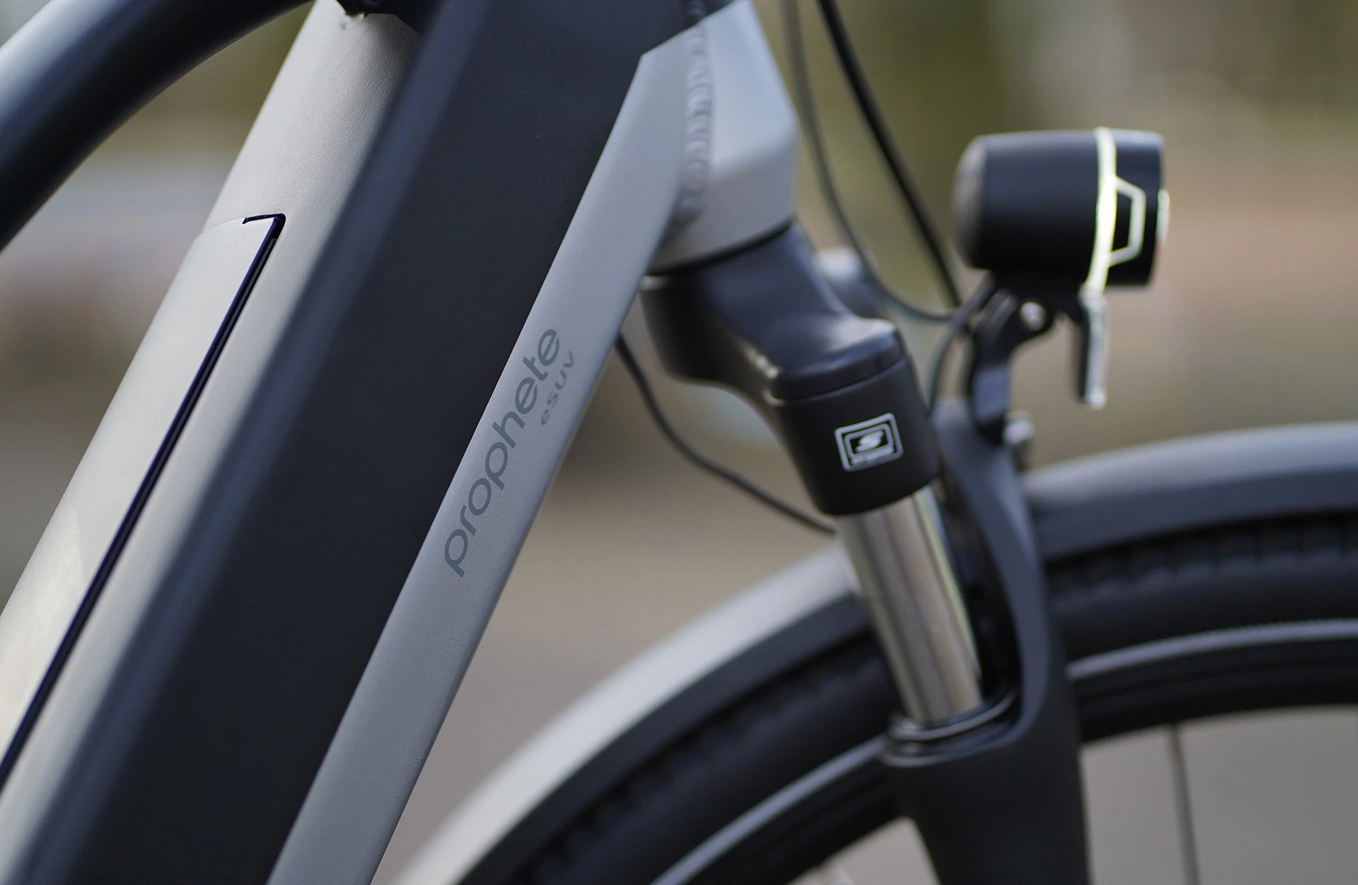 Bildausschnitt Detailansicht Scheinwerfer und Federgabel im Anschnitt mit Prophete Logo am Unterrohr vor unscharfem Hintergrund