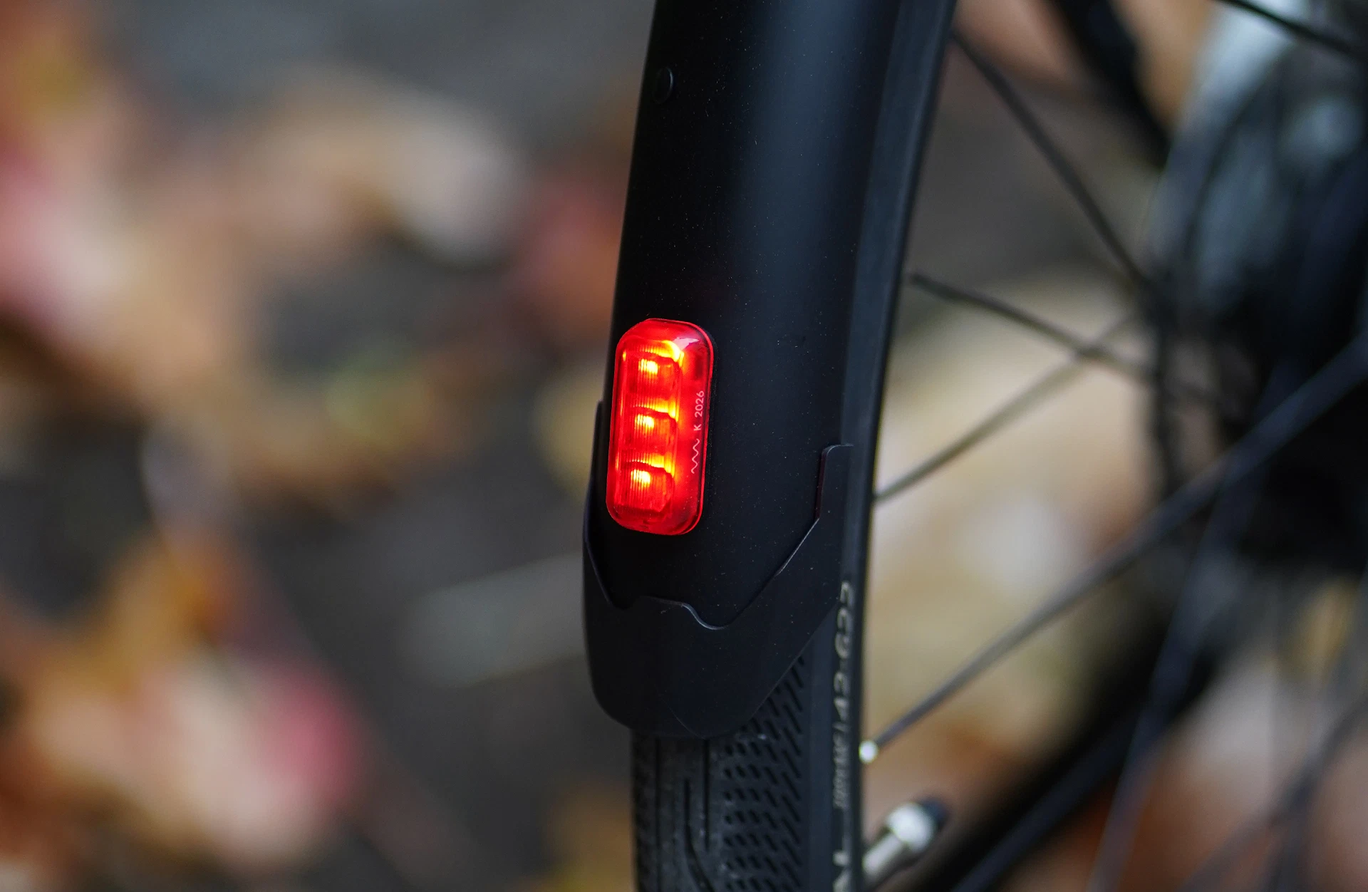 Bildausschnitt Leuchtendes rotes LED-Rücklicht integriert im hinteren Schutzblech mit unscharfem, waldigem Hintergrund