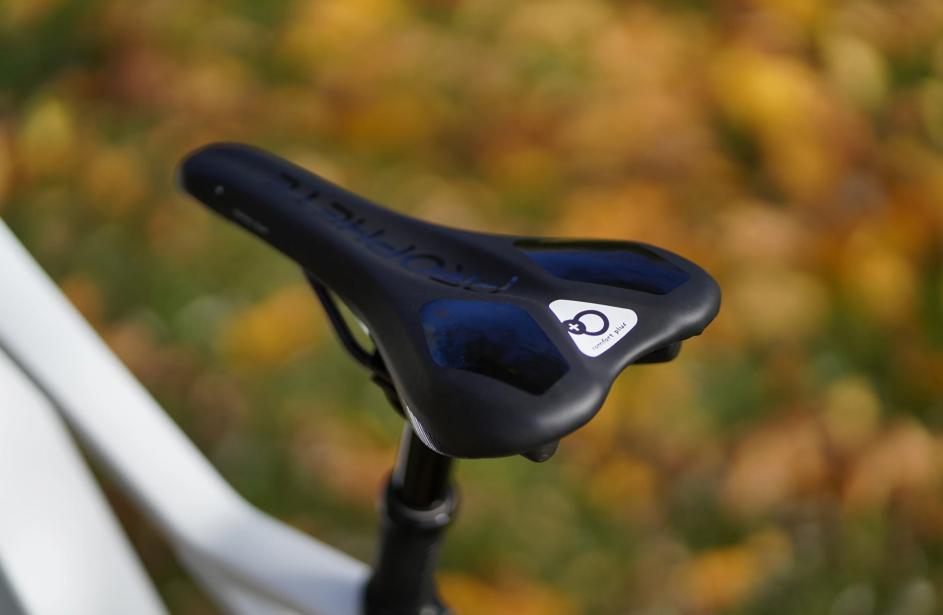 Bildausschnitt ergonomischer Comfort Plus Sattel von Prophete auf Sattelstütze vor waldigem Untergrund