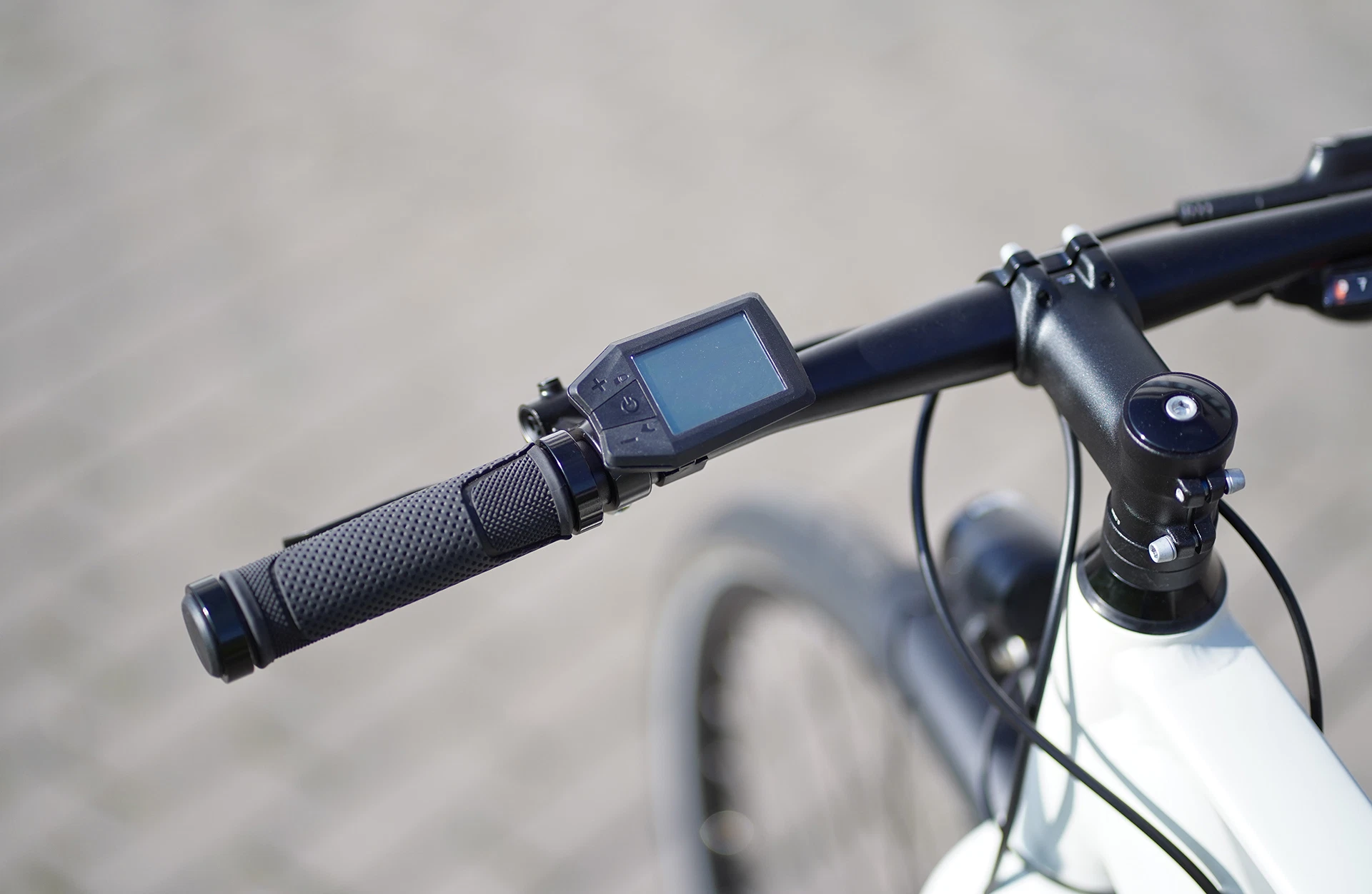 Bildausschnitt LCD-Display am Lenker mit rutschfesten Griffen und A-Head Vorbau vor unscharfem Hintergrund