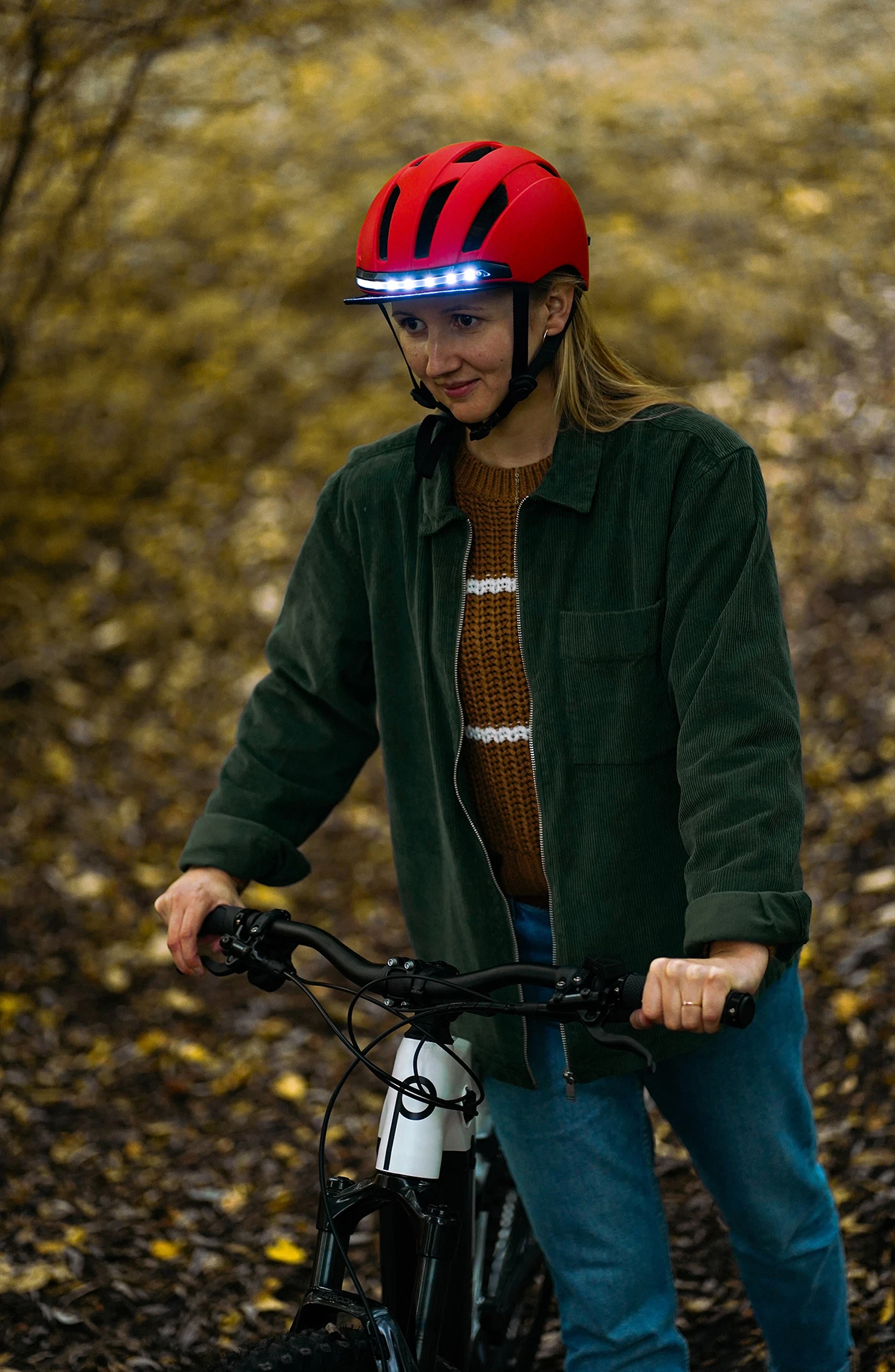 Fahrradhelm rot getragen von Frau mit Fahrrad im Wald - Ansicht von vorne
