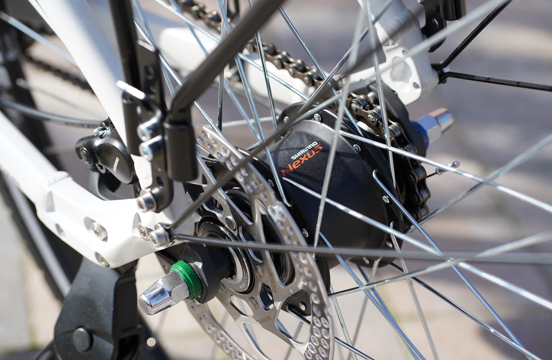 Bildausschnitt Hinterrad mit Shimano Nexus Schaltnabe, Scheibenbremse und Kette vor grauem, unscharfem Hintergrund