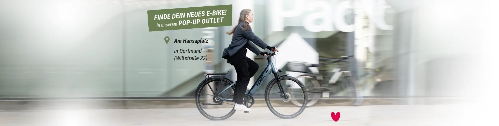 Person fährt mit einem E-Bike vor einem Geschäft, Werbebanner für Pop-up-Outlet in Dortmund am Hansaplatz (Wißstraße 22)